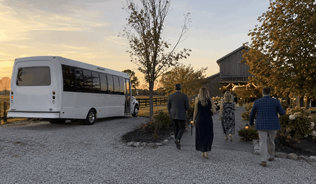 wedding shuttle bus arriving at a rural barn venue near indianapolis with guests walking toward string lights and open fields