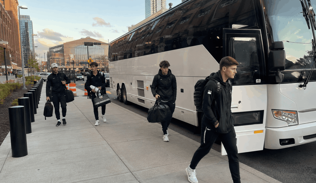 sports team boarding a white charter bus for team travel in Indianapolis